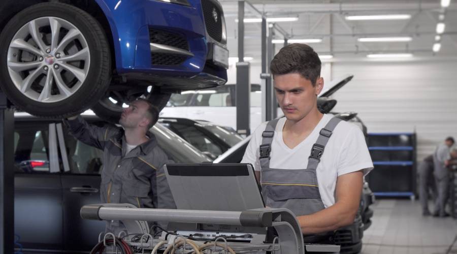 Monteur is aan het werk Met de laptop de auto uitlezen